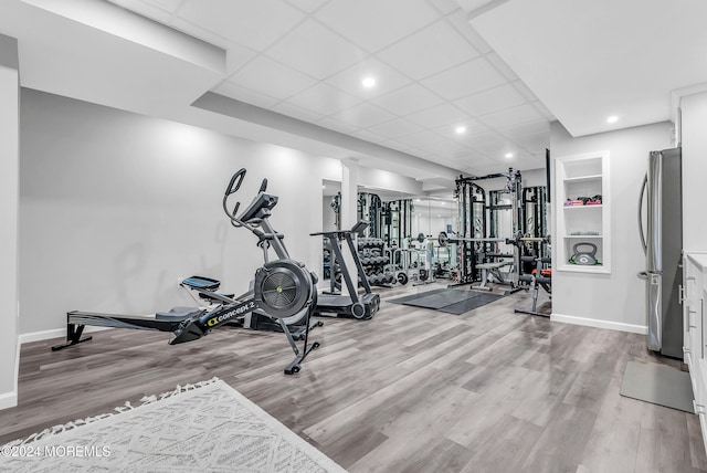 exercise room featuring a paneled ceiling and light hardwood / wood-style flooring