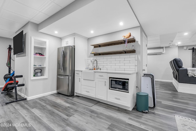 kitchen featuring built in microwave, built in features, stainless steel refrigerator with ice dispenser, a wall mounted AC, and white cabinets