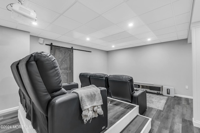 home theater room featuring a barn door, a paneled ceiling, and dark hardwood / wood-style flooring