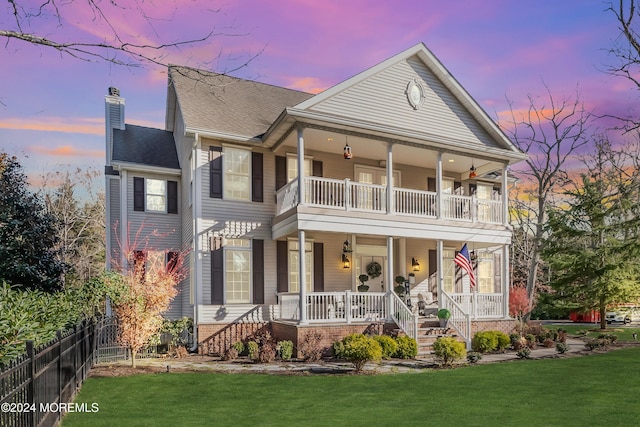 view of front of property featuring a lawn, covered porch, and a balcony