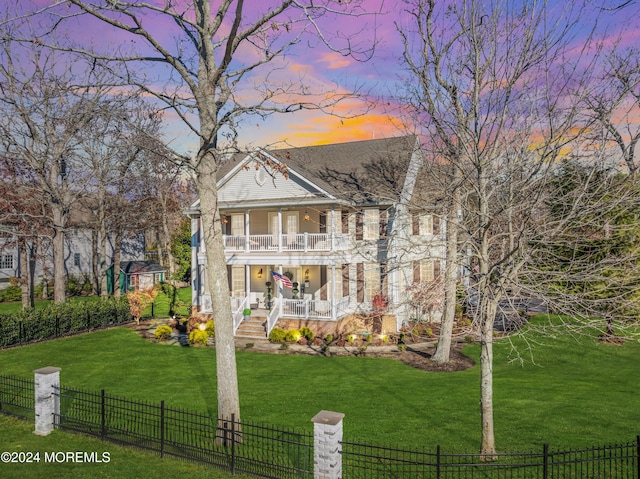 neoclassical / greek revival house featuring covered porch, a yard, and a balcony