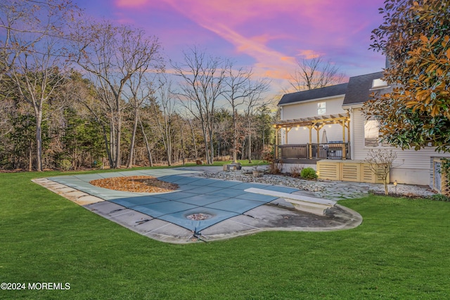 pool at dusk featuring a lawn, a patio area, a pergola, and a wooden deck