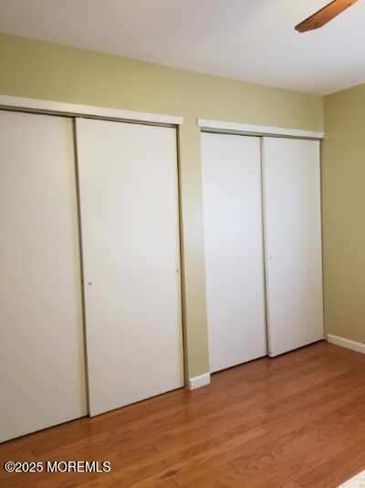 33 Penwood Dr Unit 55, Whiting, NJ 08759 - unfurnished bedroom with multiple closets, light wood finished floors, baseboards, and a ceiling fan