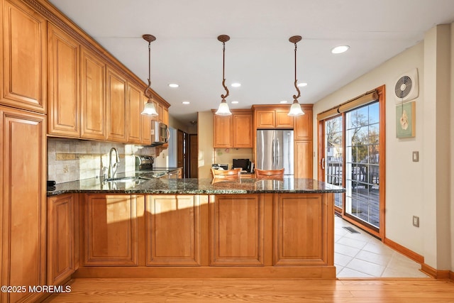 kitchen with sink, decorative light fixtures, tasteful backsplash, dark stone counters, and appliances with stainless steel finishes