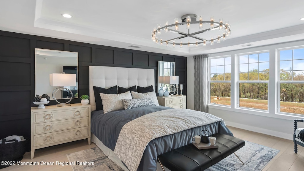 bedroom with a raised ceiling, ornamental molding, and a notable chandelier