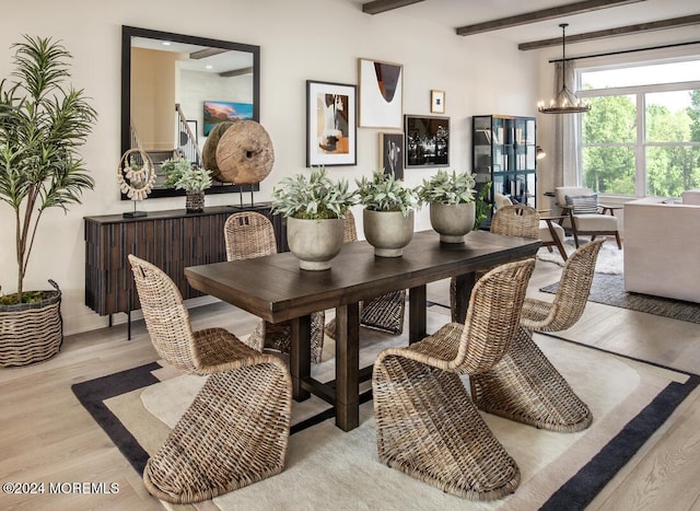 dining area featuring beamed ceiling, light hardwood / wood-style floors, and an inviting chandelier