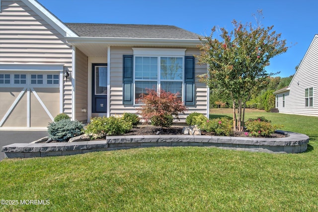 view of front of property featuring an attached garage and a front lawn