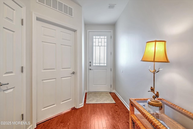 doorway to outside with hardwood / wood-style flooring, visible vents, and baseboards