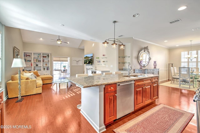 kitchen with hanging light fixtures, stainless steel dishwasher, and an island with sink