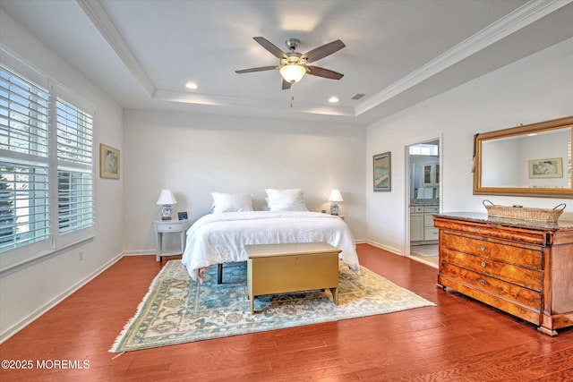 bedroom with baseboards, a tray ceiling, wood finished floors, and crown molding