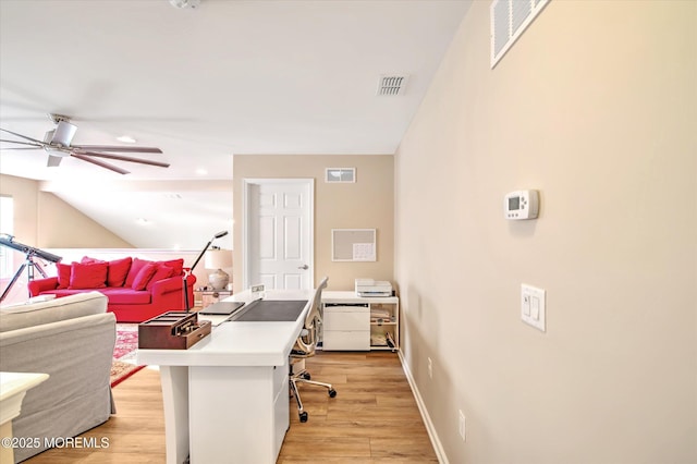 office area featuring light wood-style flooring, visible vents, and vaulted ceiling