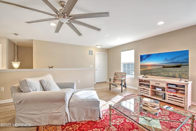 living room featuring light wood finished floors, baseboards, and visible vents