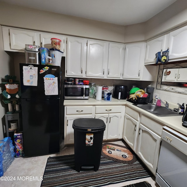 kitchen with white cabinets, black refrigerator, and dishwashing machine