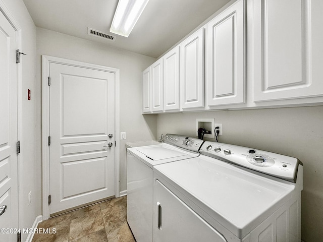 clothes washing area featuring visible vents, baseboards, cabinet space, and washer and dryer