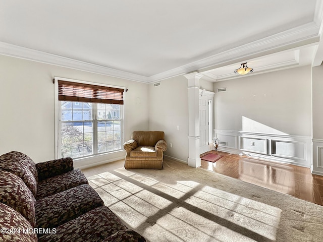 living area featuring a decorative wall, wainscoting, decorative columns, and crown molding