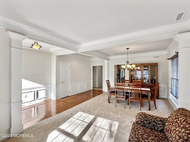 dining room with hardwood / wood-style floors, decorative columns, ornamental molding, and an inviting chandelier