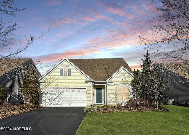 view of front of property with a lawn, cooling unit, and a garage