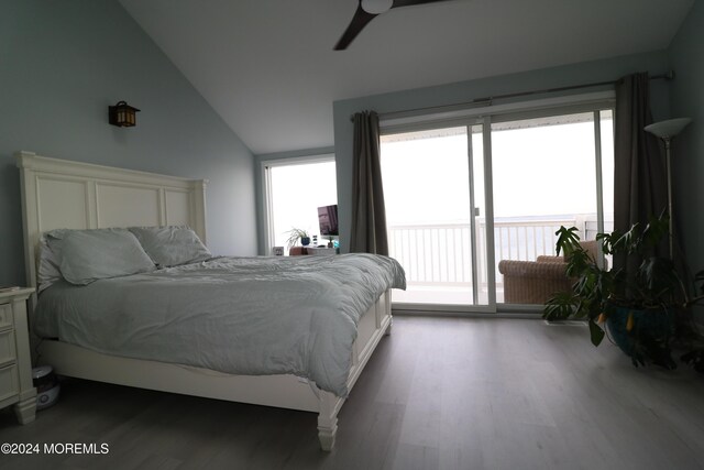 bedroom featuring access to exterior, lofted ceiling, multiple windows, and wood finished floors