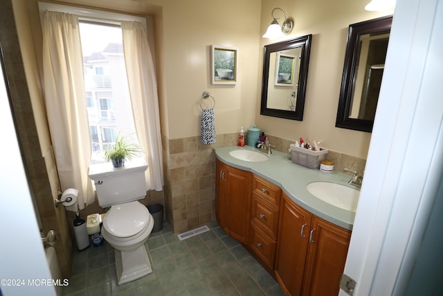 bathroom with visible vents, a sink, tile walls, and double vanity