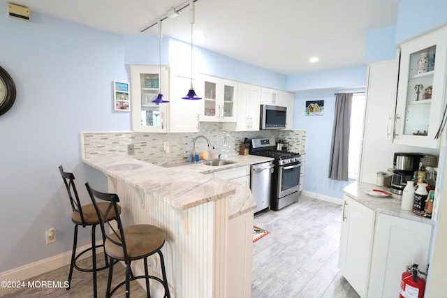 kitchen featuring a breakfast bar area, decorative backsplash, appliances with stainless steel finishes, a sink, and a peninsula