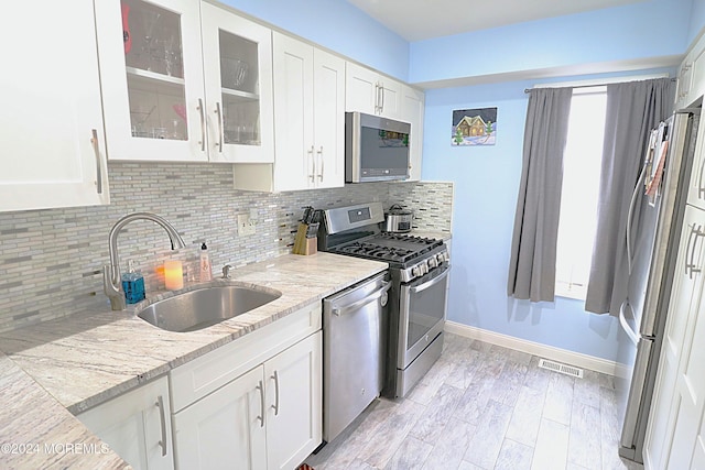 kitchen with appliances with stainless steel finishes, white cabinets, visible vents, and a sink