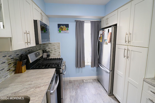 kitchen with appliances with stainless steel finishes, white cabinets, visible vents, and backsplash