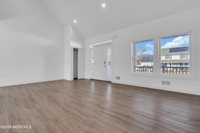 unfurnished living room featuring hardwood / wood-style flooring and high vaulted ceiling