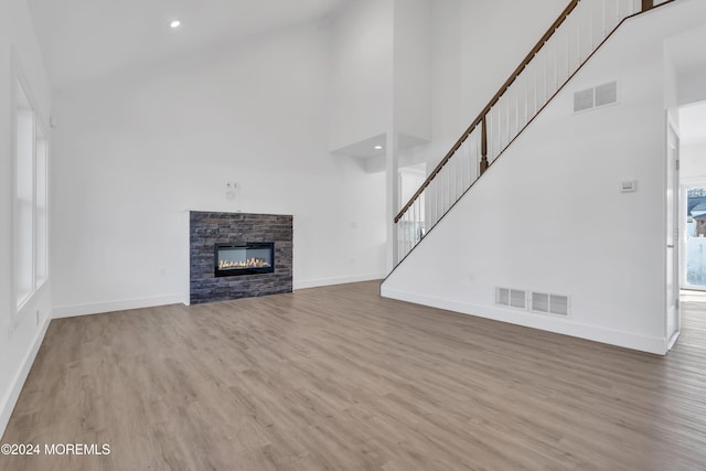 unfurnished living room featuring a fireplace, hardwood / wood-style floors, high vaulted ceiling, and a healthy amount of sunlight