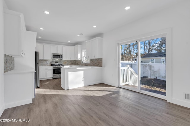 kitchen featuring kitchen peninsula, light wood-type flooring, white cabinetry, and stainless steel appliances