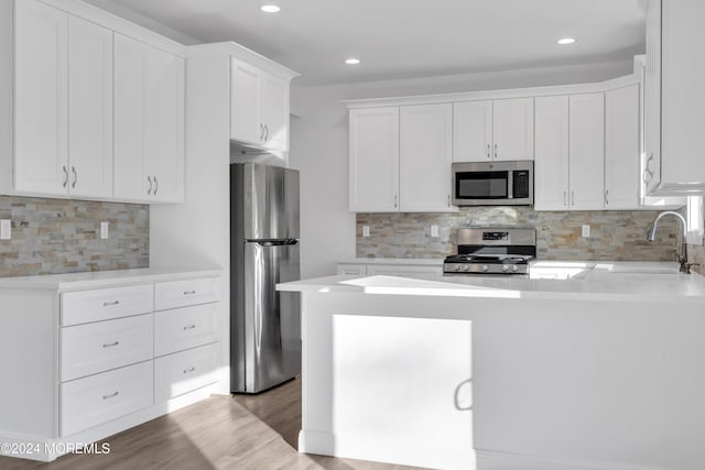 kitchen with sink, stainless steel appliances, tasteful backsplash, light hardwood / wood-style flooring, and white cabinets