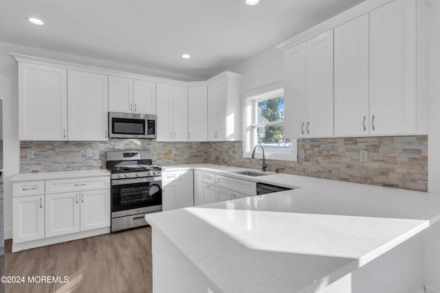 kitchen with white cabinets, light wood-type flooring, stainless steel appliances, and sink