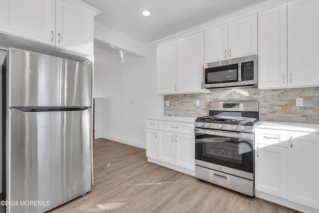 kitchen featuring appliances with stainless steel finishes, light hardwood / wood-style flooring, white cabinetry, and tasteful backsplash