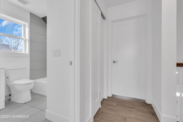 bathroom with hardwood / wood-style flooring, toilet, and bathing tub / shower combination