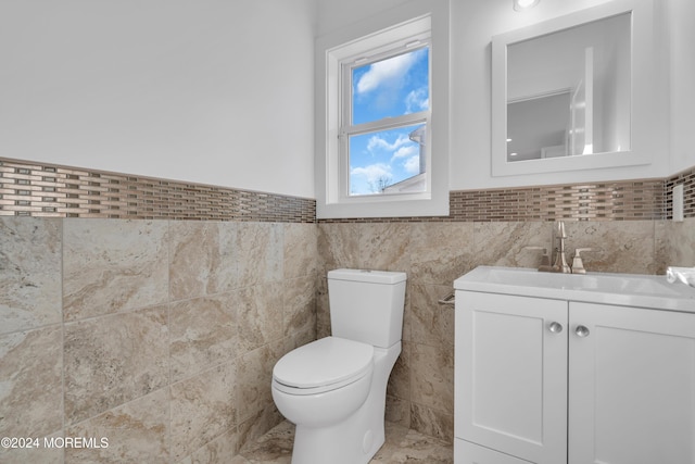 bathroom featuring vanity, toilet, and tile walls