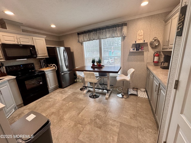 kitchen featuring recessed lighting, black appliances, light countertops, and ornamental molding