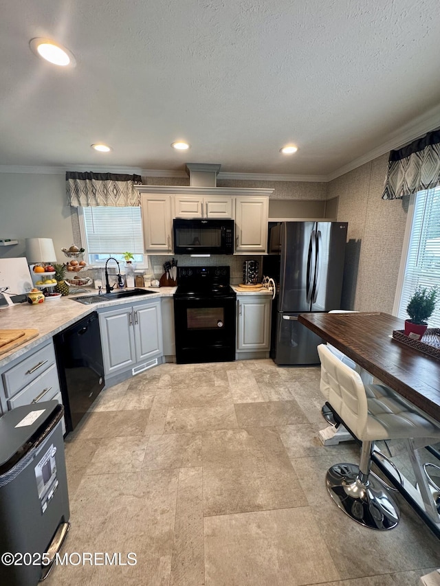 kitchen featuring a textured ceiling, light countertops, ornamental molding, a sink, and black appliances