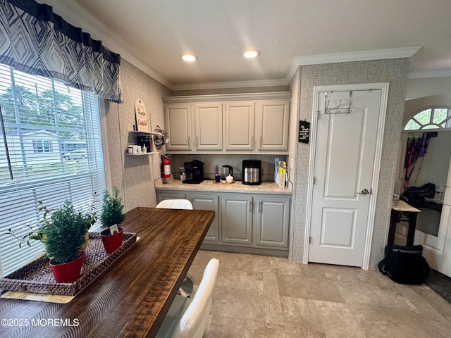 kitchen with light countertops, white cabinets, ornamental molding, and plenty of natural light