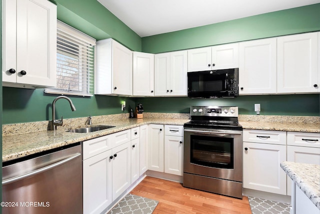 kitchen featuring white cabinetry, sink, stainless steel appliances, light stone counters, and light hardwood / wood-style flooring