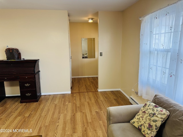 sitting room with a baseboard heating unit and light wood-type flooring