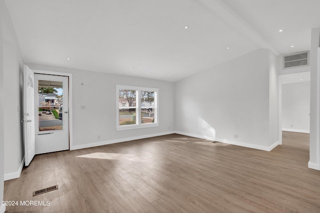 unfurnished living room featuring lofted ceiling with beams and light wood-type flooring