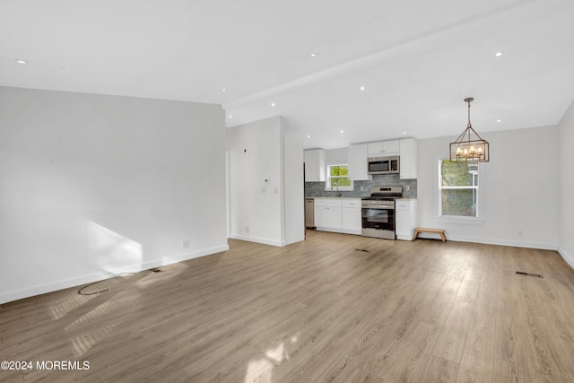 unfurnished living room featuring light hardwood / wood-style floors and an inviting chandelier