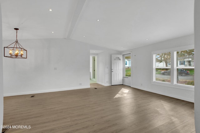 unfurnished living room featuring lofted ceiling with beams, hardwood / wood-style flooring, and a notable chandelier