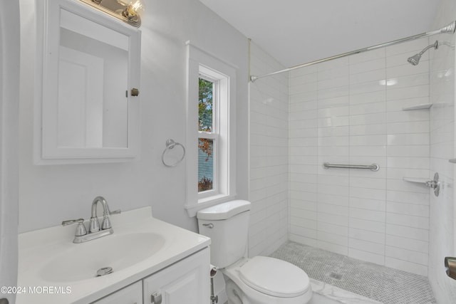 bathroom with tiled shower, vanity, and toilet