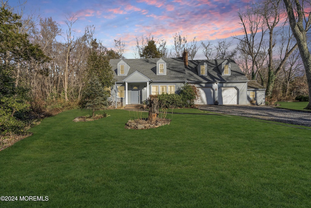 cape cod house with a lawn and a garage