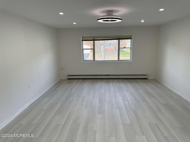 empty room featuring light wood-type flooring and a baseboard radiator