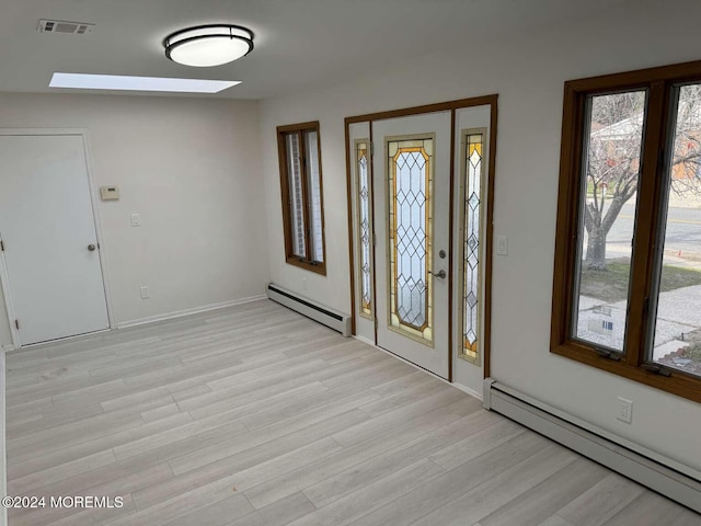 entryway with light hardwood / wood-style floors, a skylight, and a baseboard heating unit