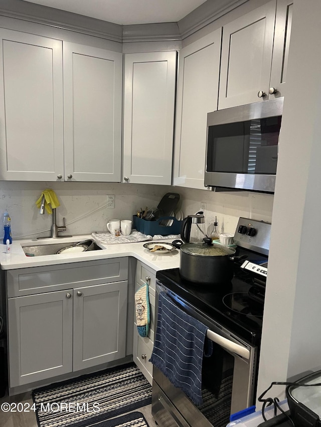 kitchen with stainless steel appliances, gray cabinets, tasteful backsplash, and sink