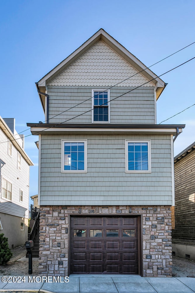 exterior space with driveway, stone siding, and an attached garage