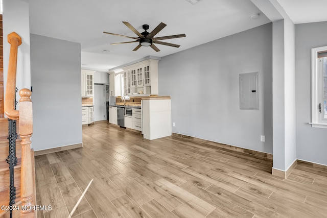 unfurnished living room with ceiling fan, sink, electric panel, and light hardwood / wood-style floors