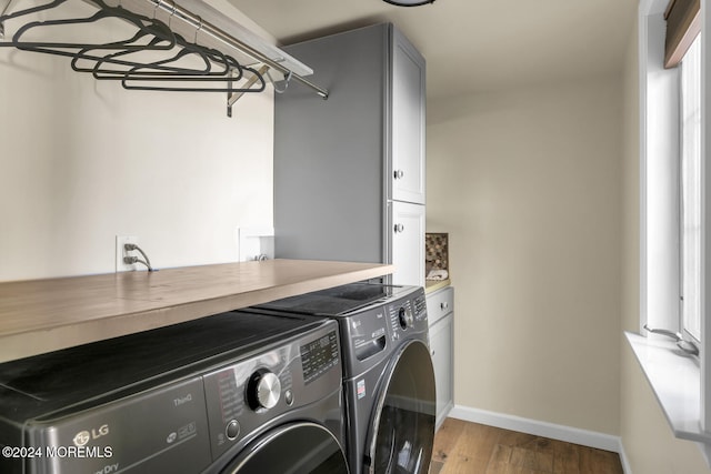 washroom with washer and dryer, hardwood / wood-style floors, and cabinets